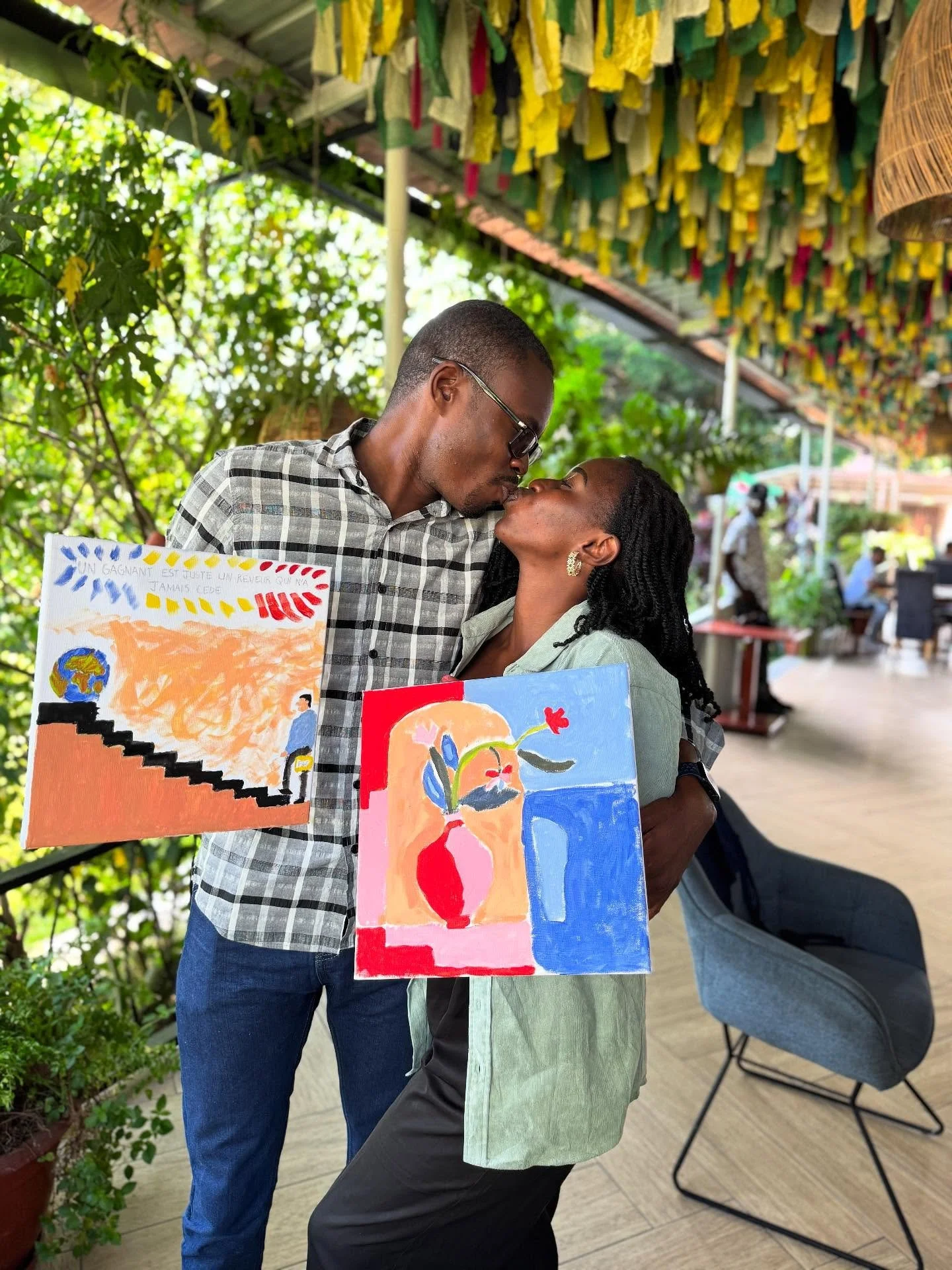 Couple sharing a kiss while holding their finished paintings
