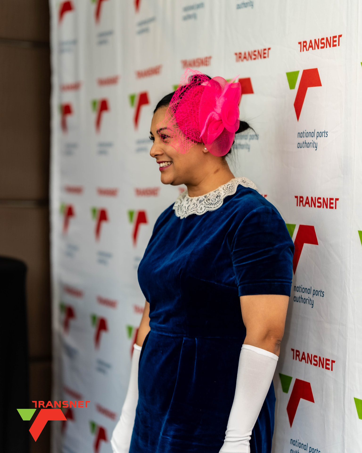 Smiling guest in a pink fascinator at a corporate event