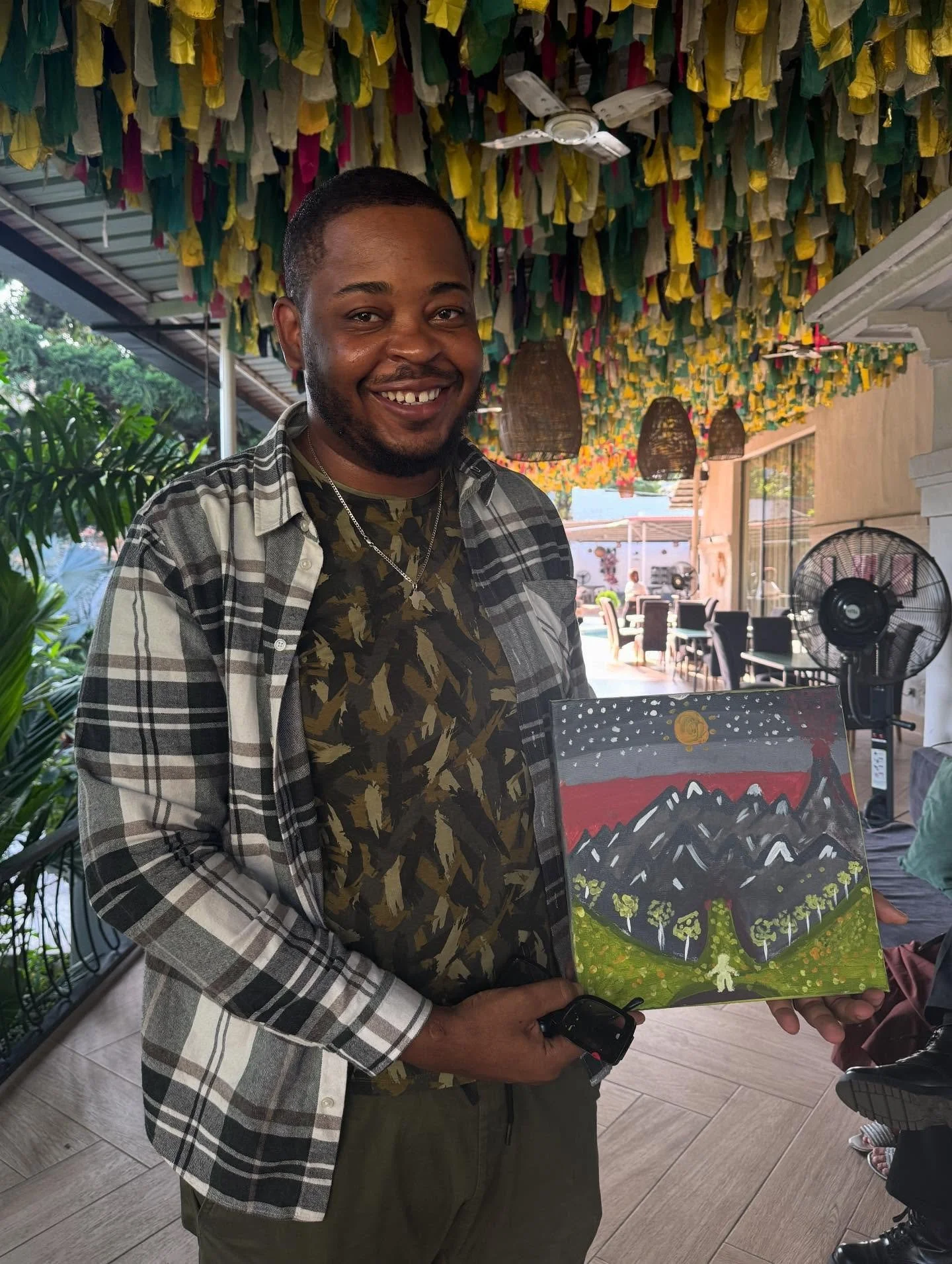Smiling guest holding his mountain landscape painting