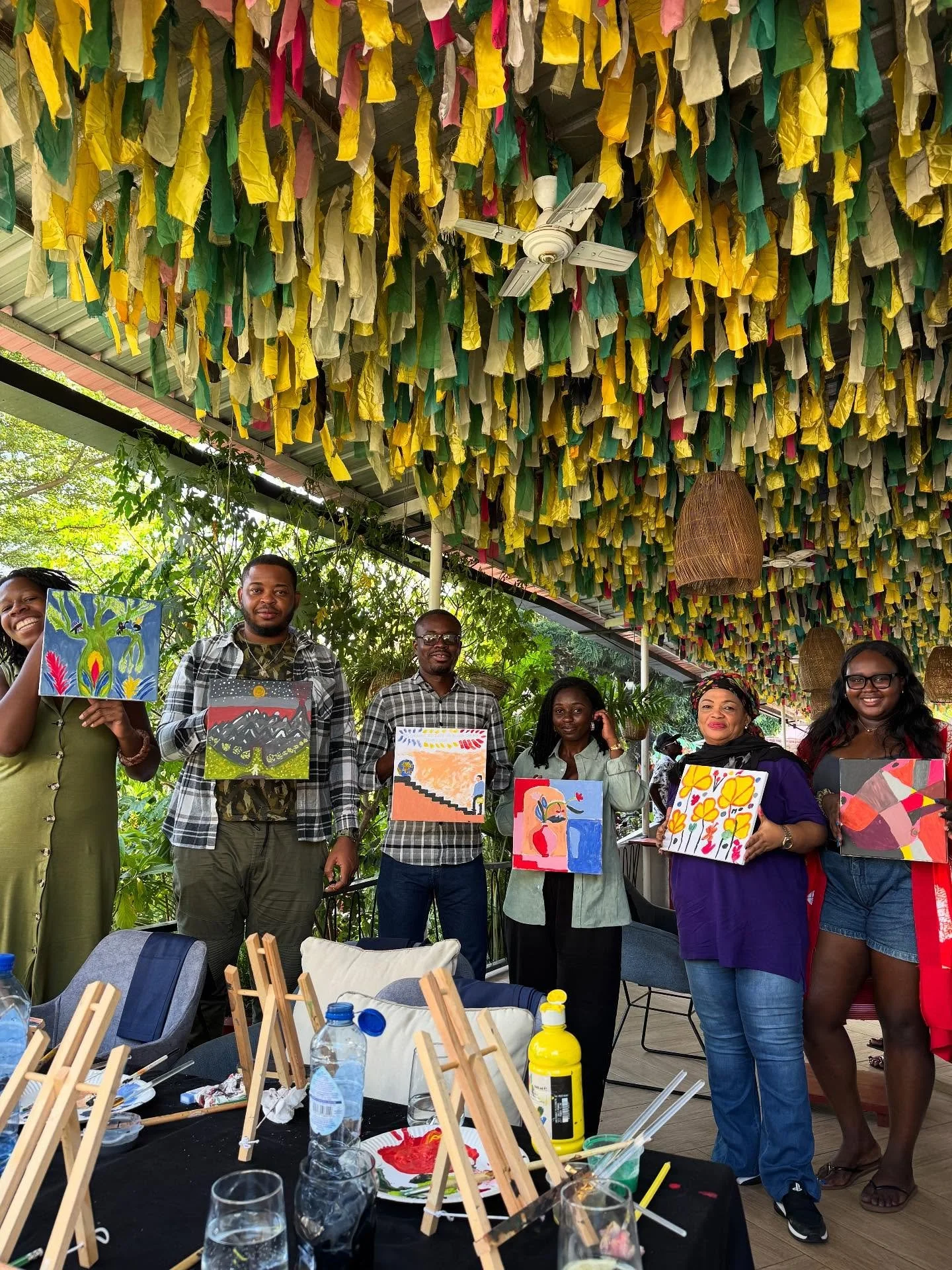 Group of guests showing their paintings beneath colourful fabric ribbons