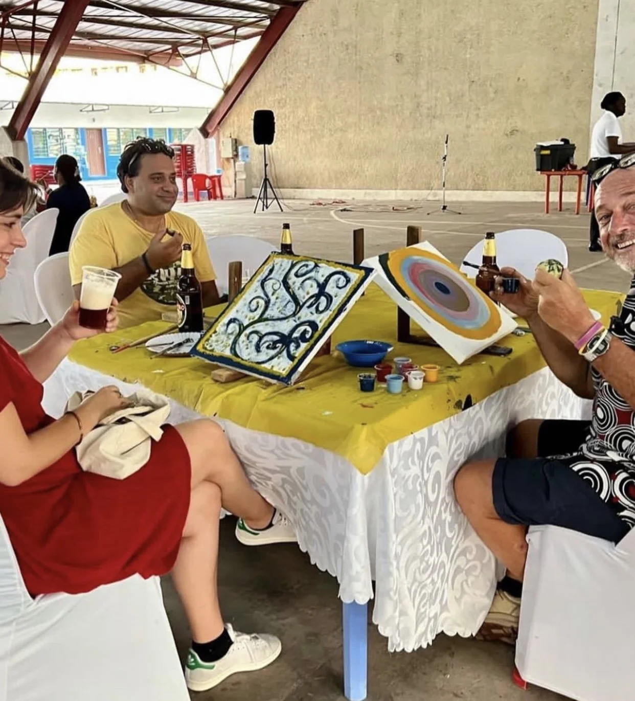 Friends enjoying drinks beside their canvases