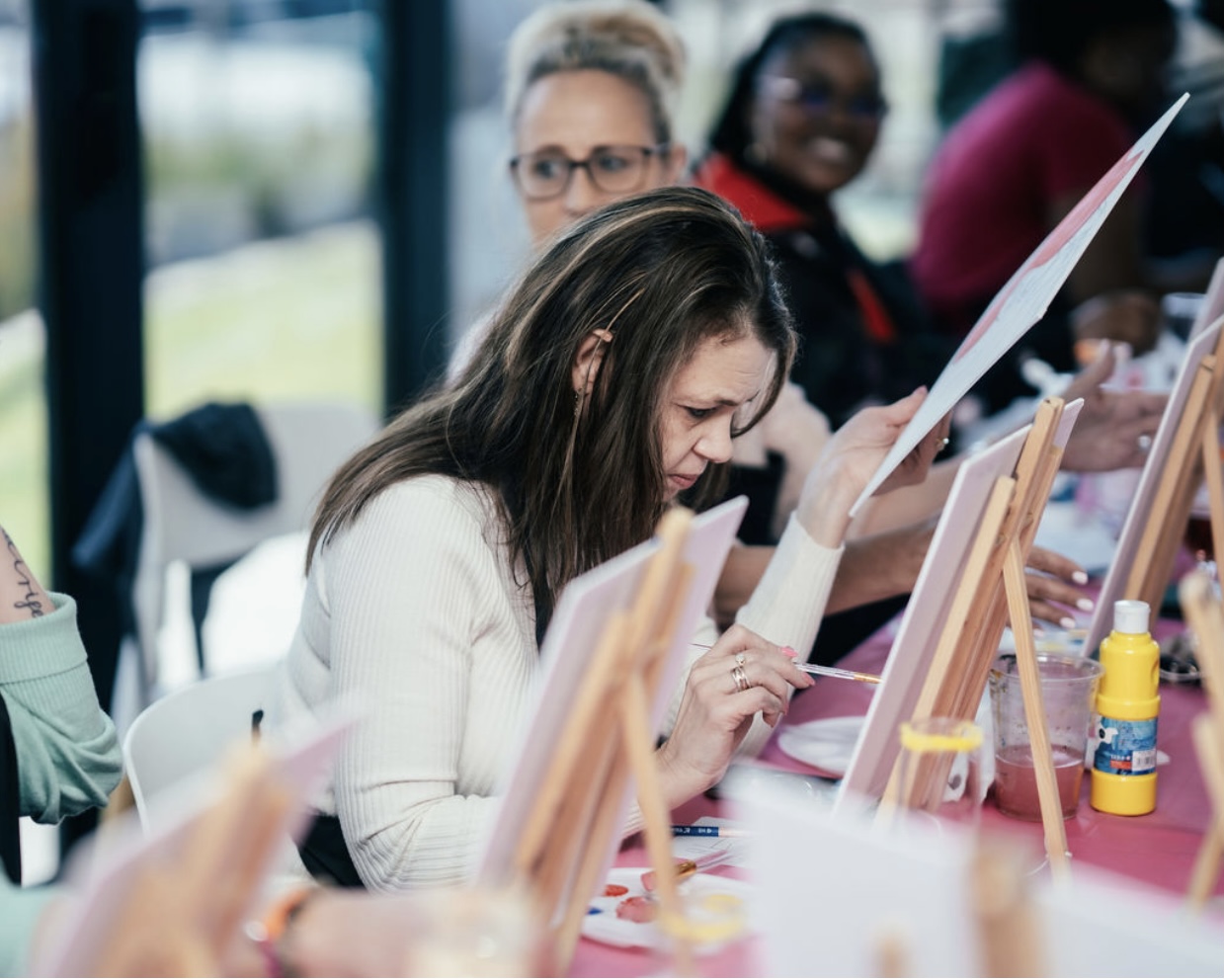 Guest concentrating on her canvas at a team paint session
